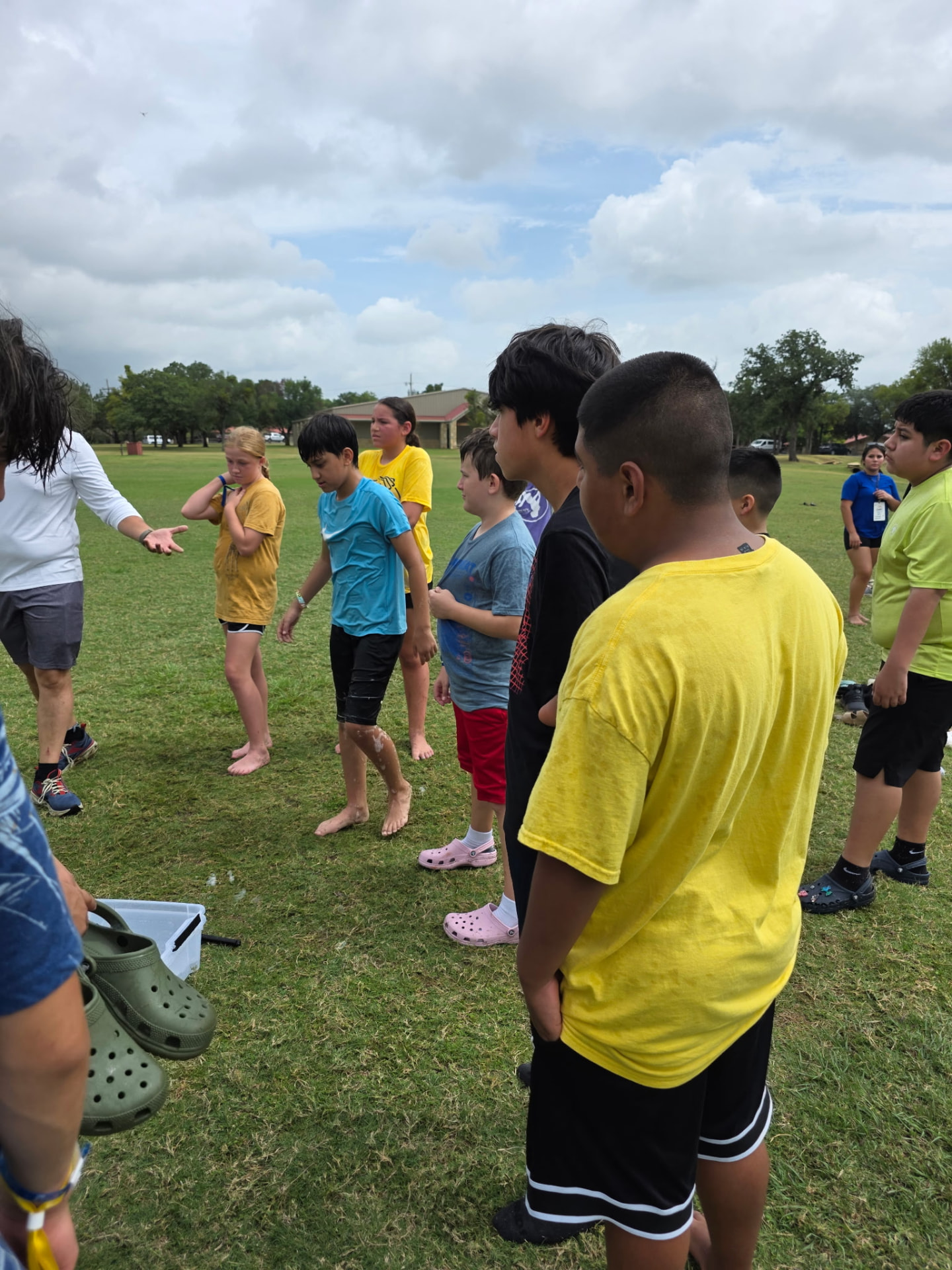 Students gathered on the field listening to a leader give game instructions