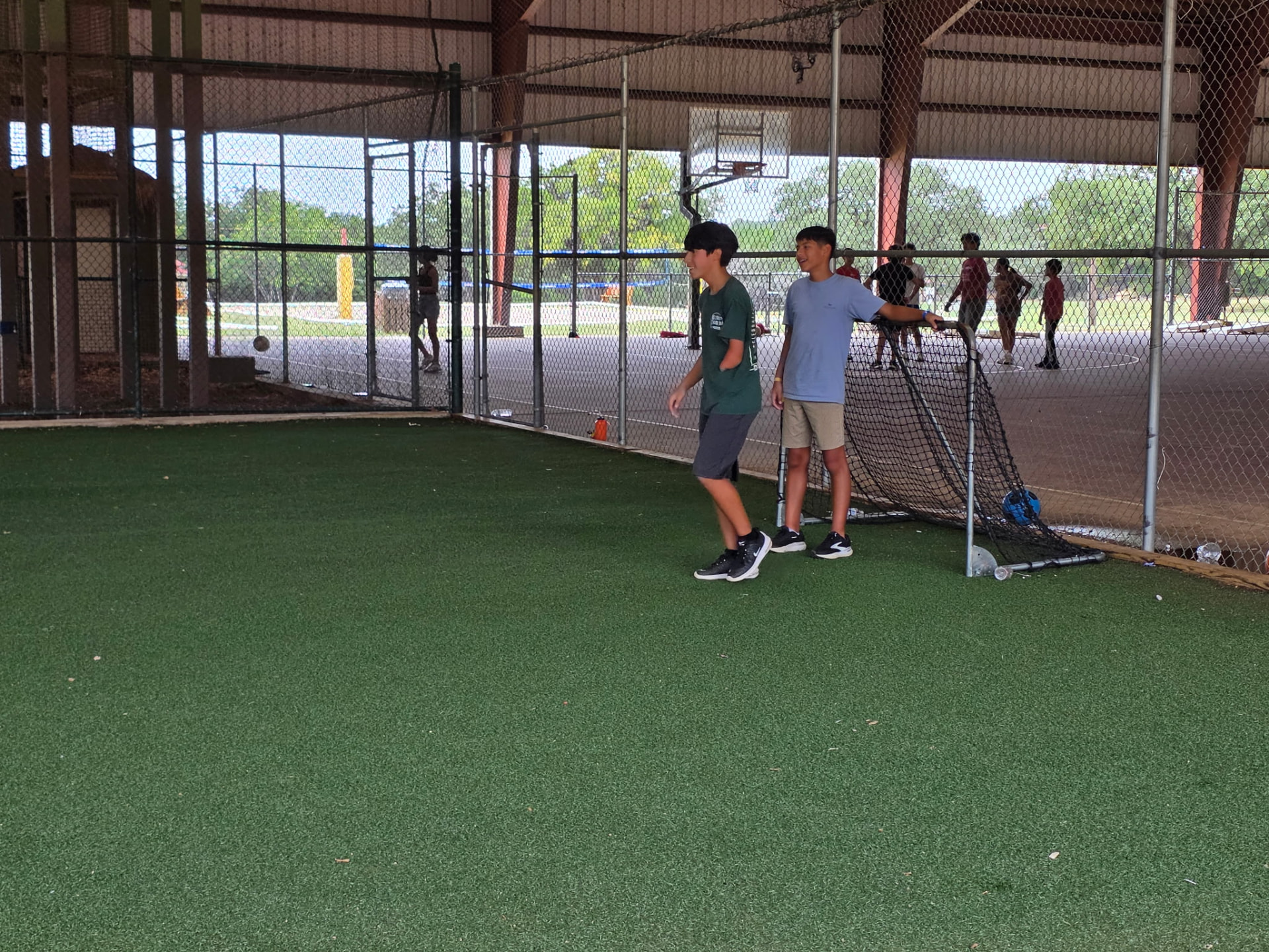 Two students playing soccer on the covered turf field at summer camp