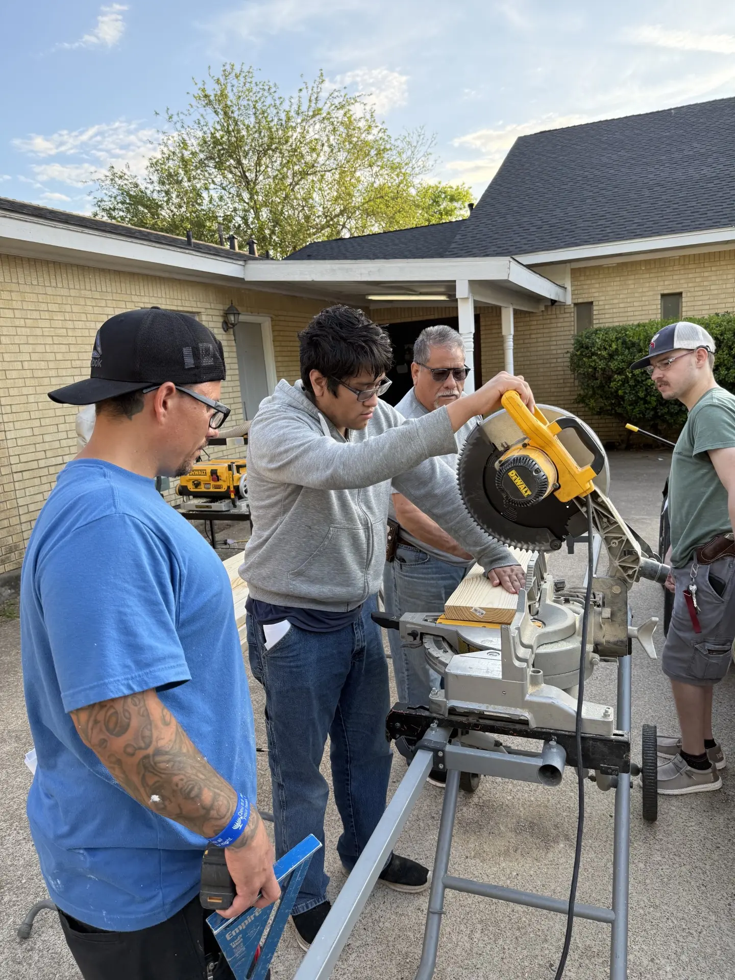 A mentor teaching a Job Corps student to use a miter saw outside the church