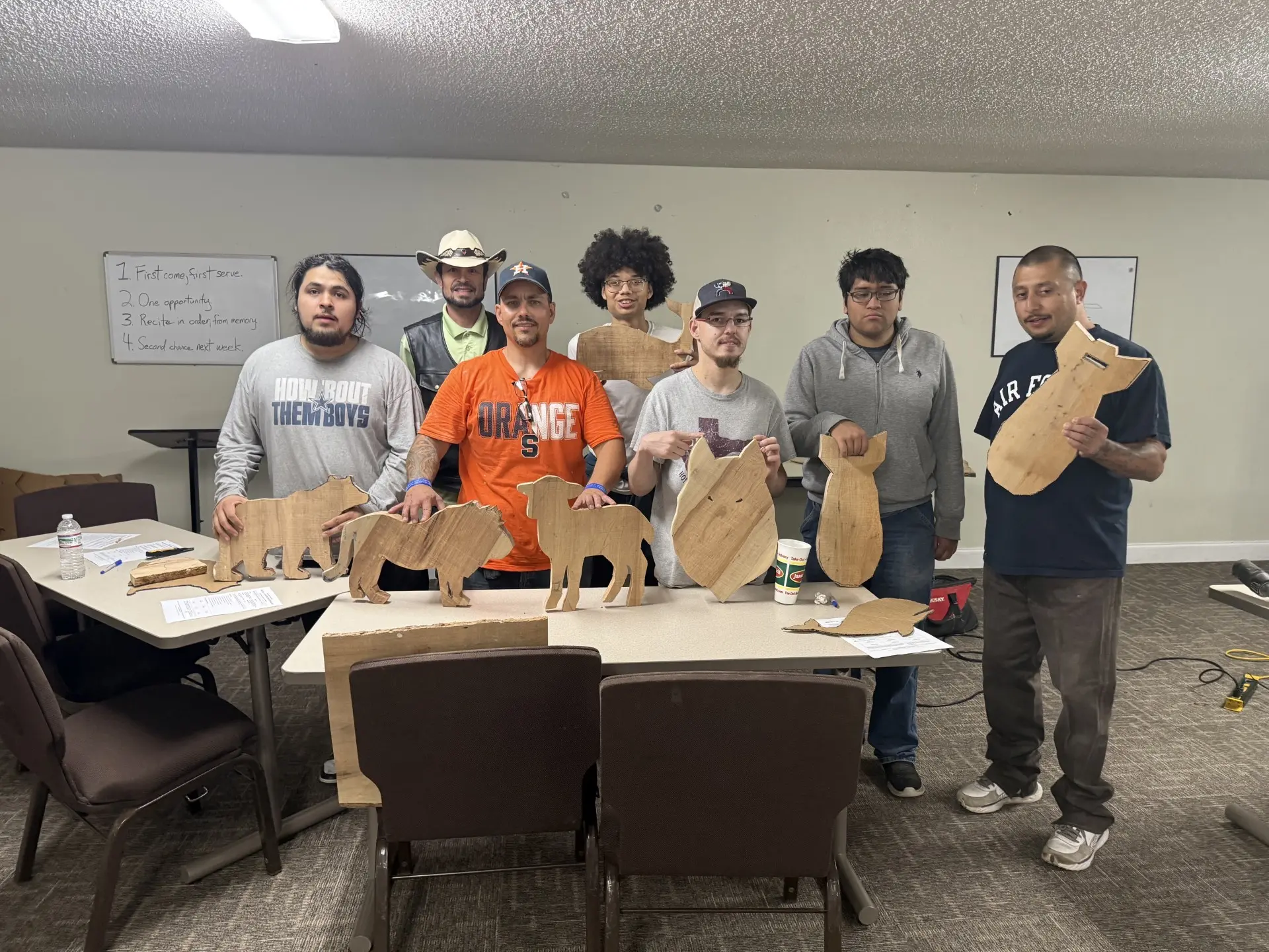 Job Corps class holding up the wooden animal cutouts they built