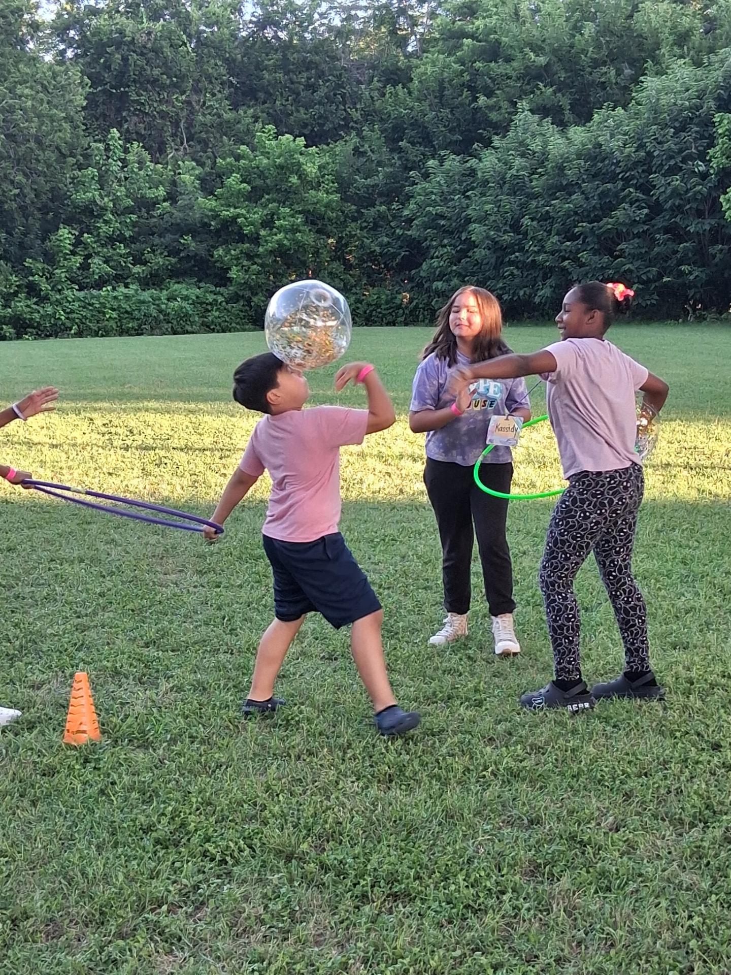 Kids laughing during an outdoor ball and hula hoop game