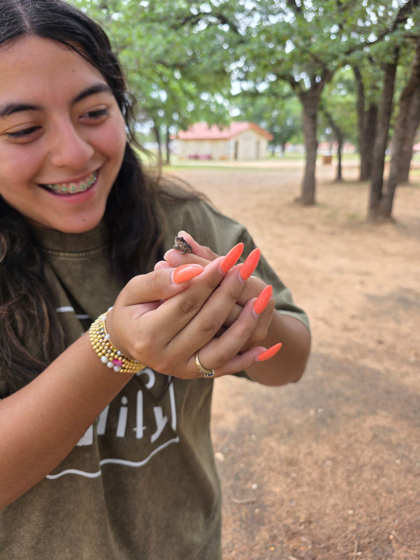 A student smiling while holding a tiny frog she found at camp