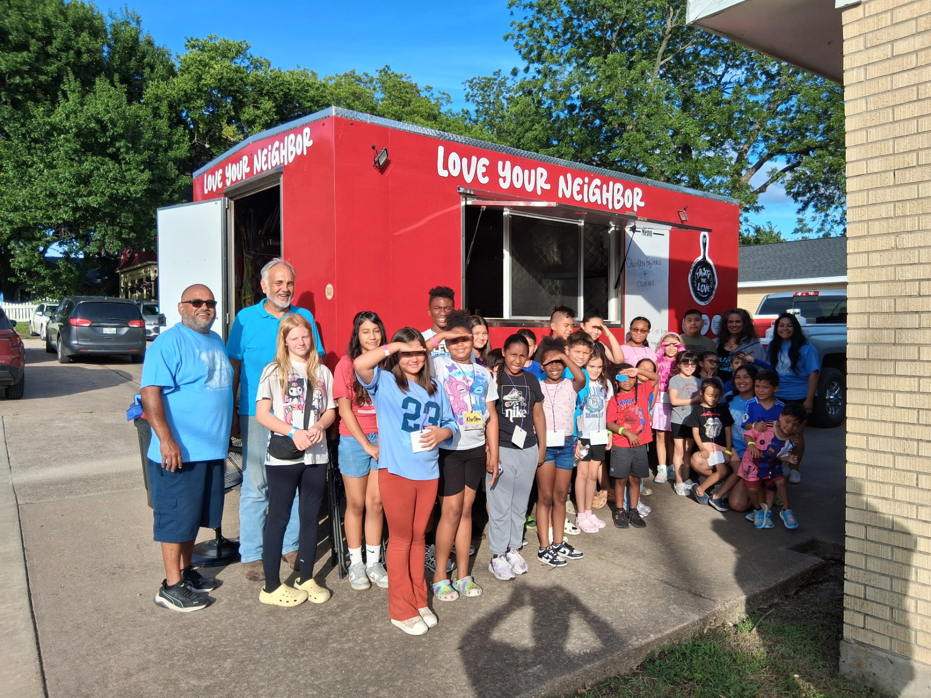 Kids and leaders posing outside the Love Your Neighbor food trailer