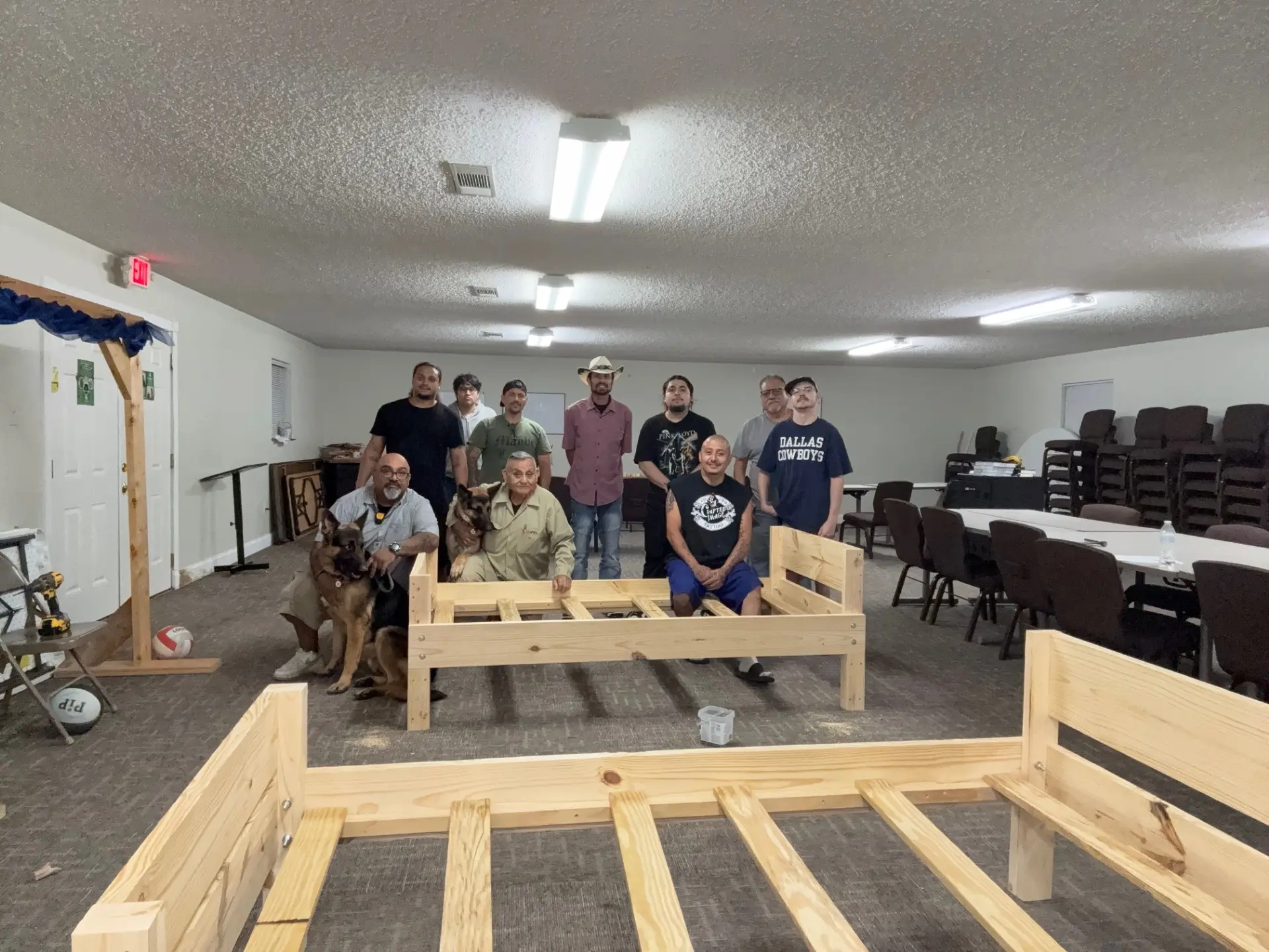 Job Corps class standing with the wooden bed frames they built in the fellowship hall