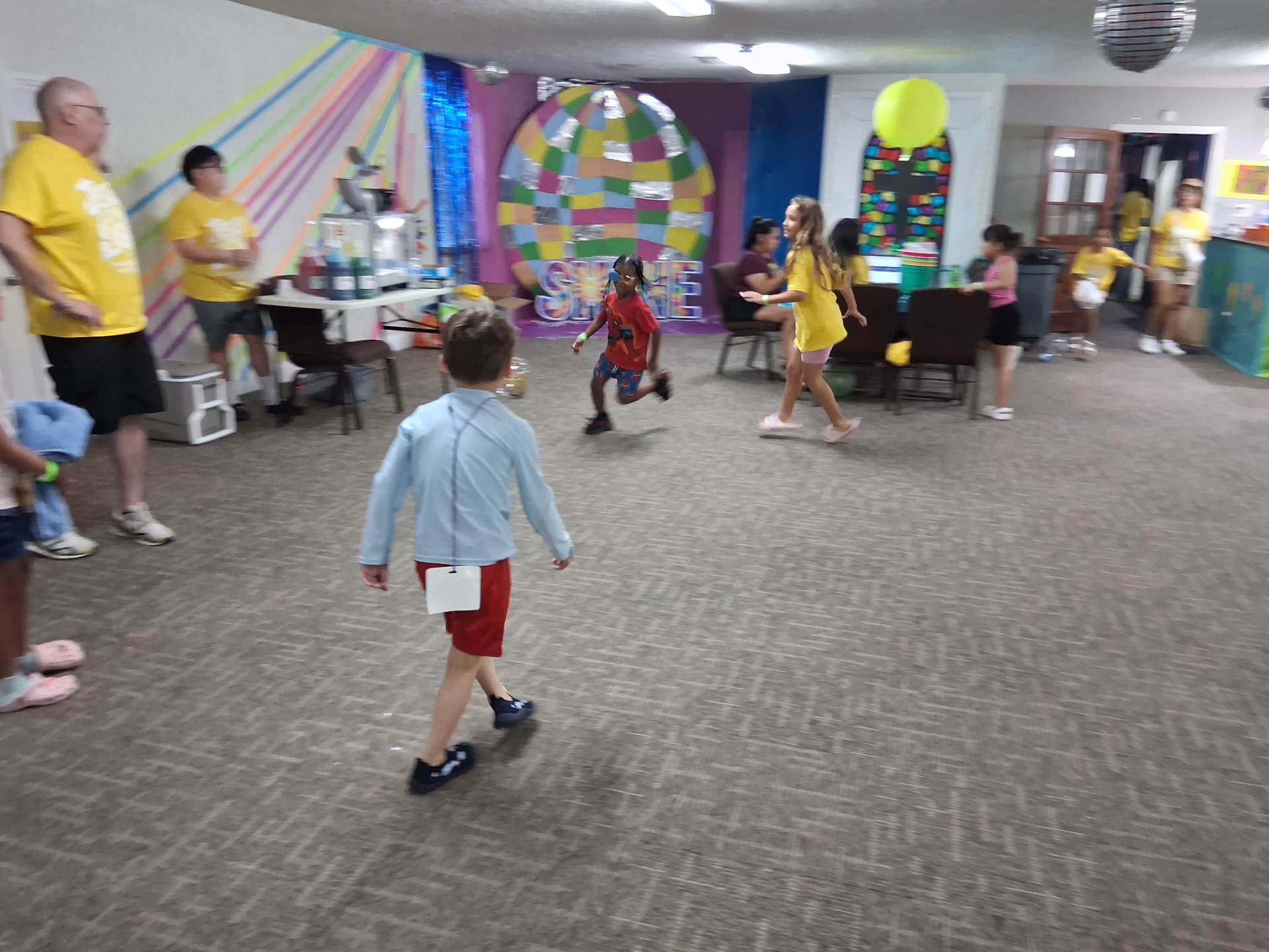 Kids and volunteers playing in the decorated fellowship hall at Vacation Bible School