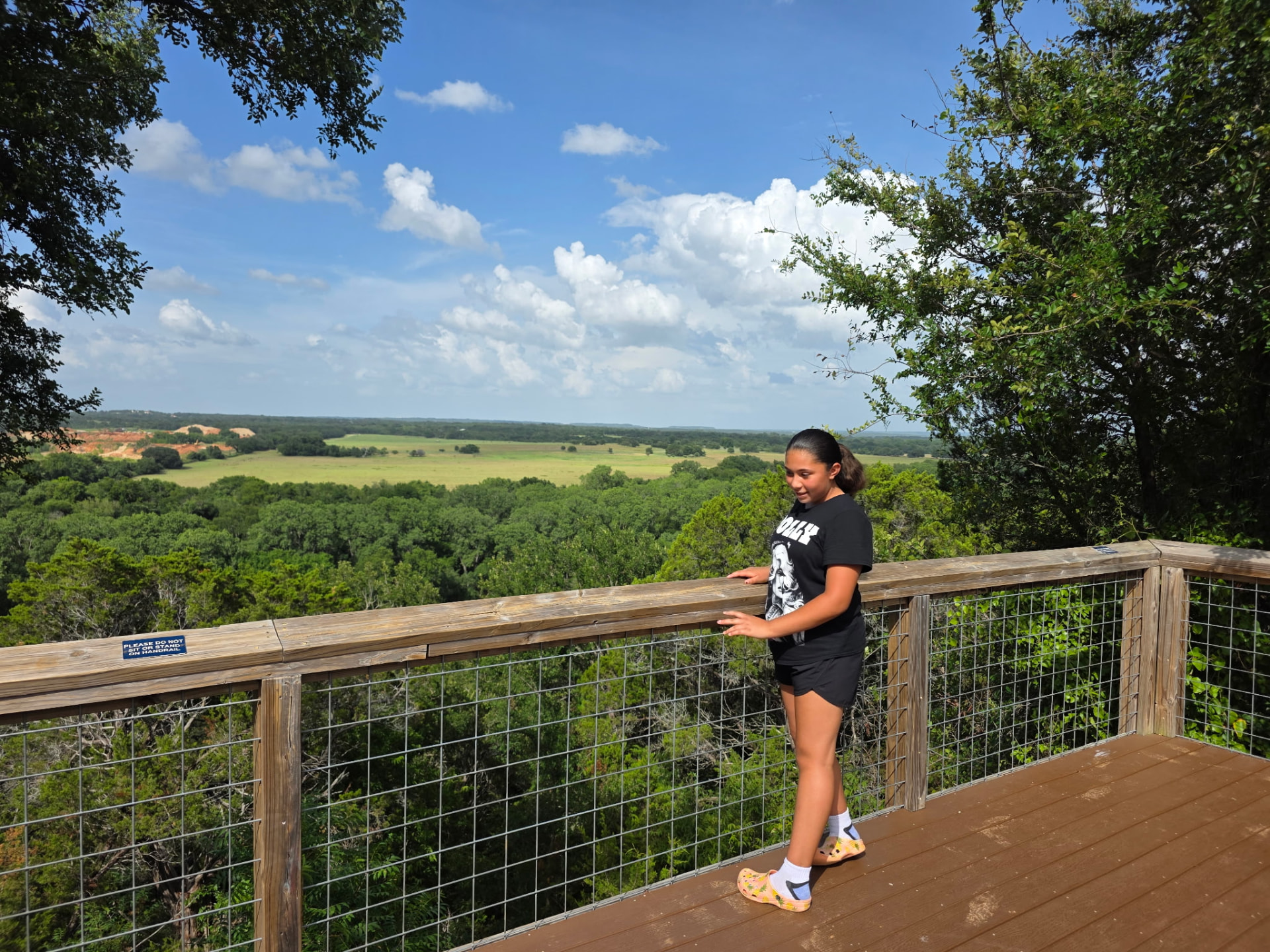 A student taking in the view from an overlook deck at camp