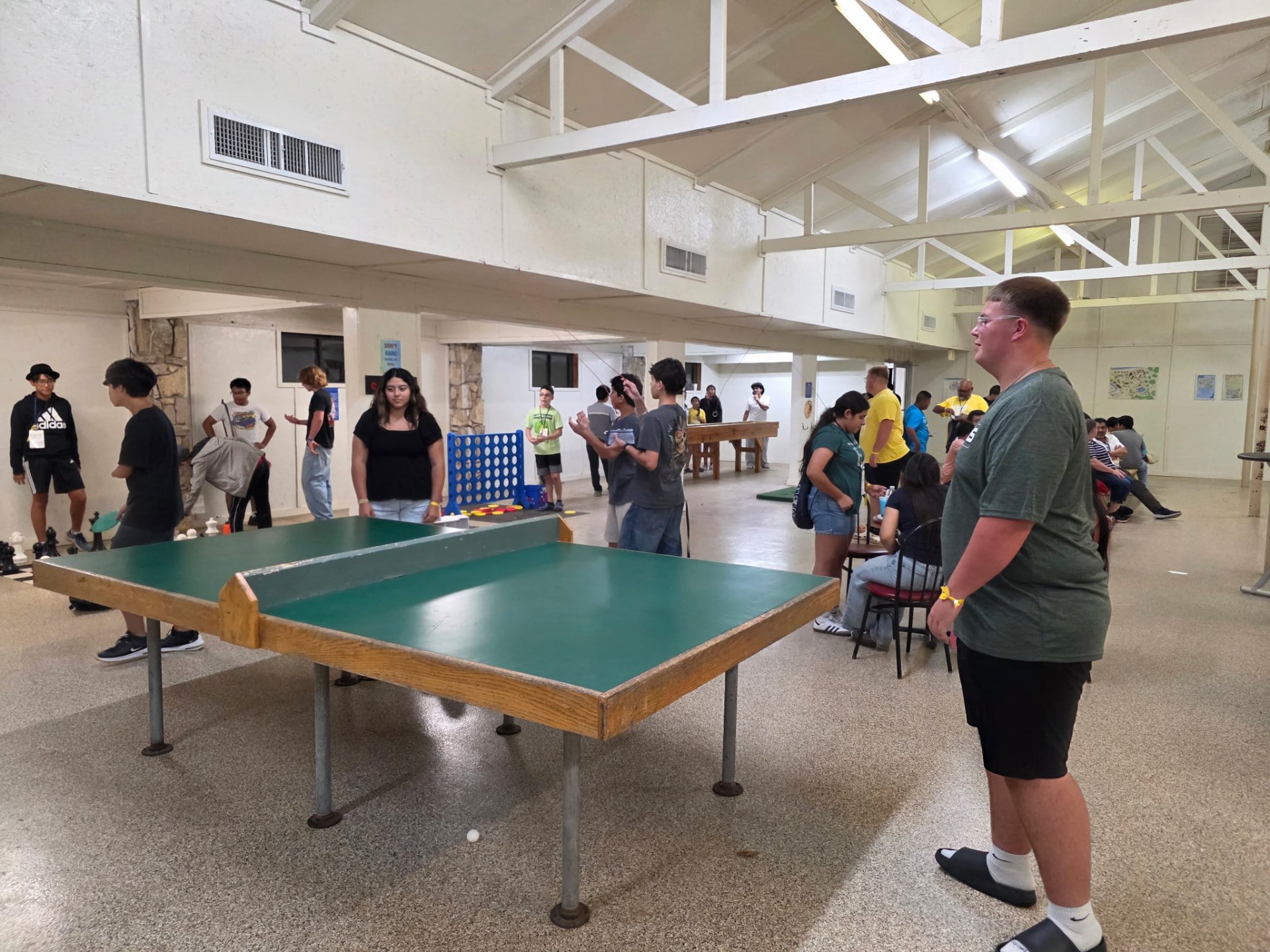 Students playing ping pong and giant Connect Four in the camp game room
