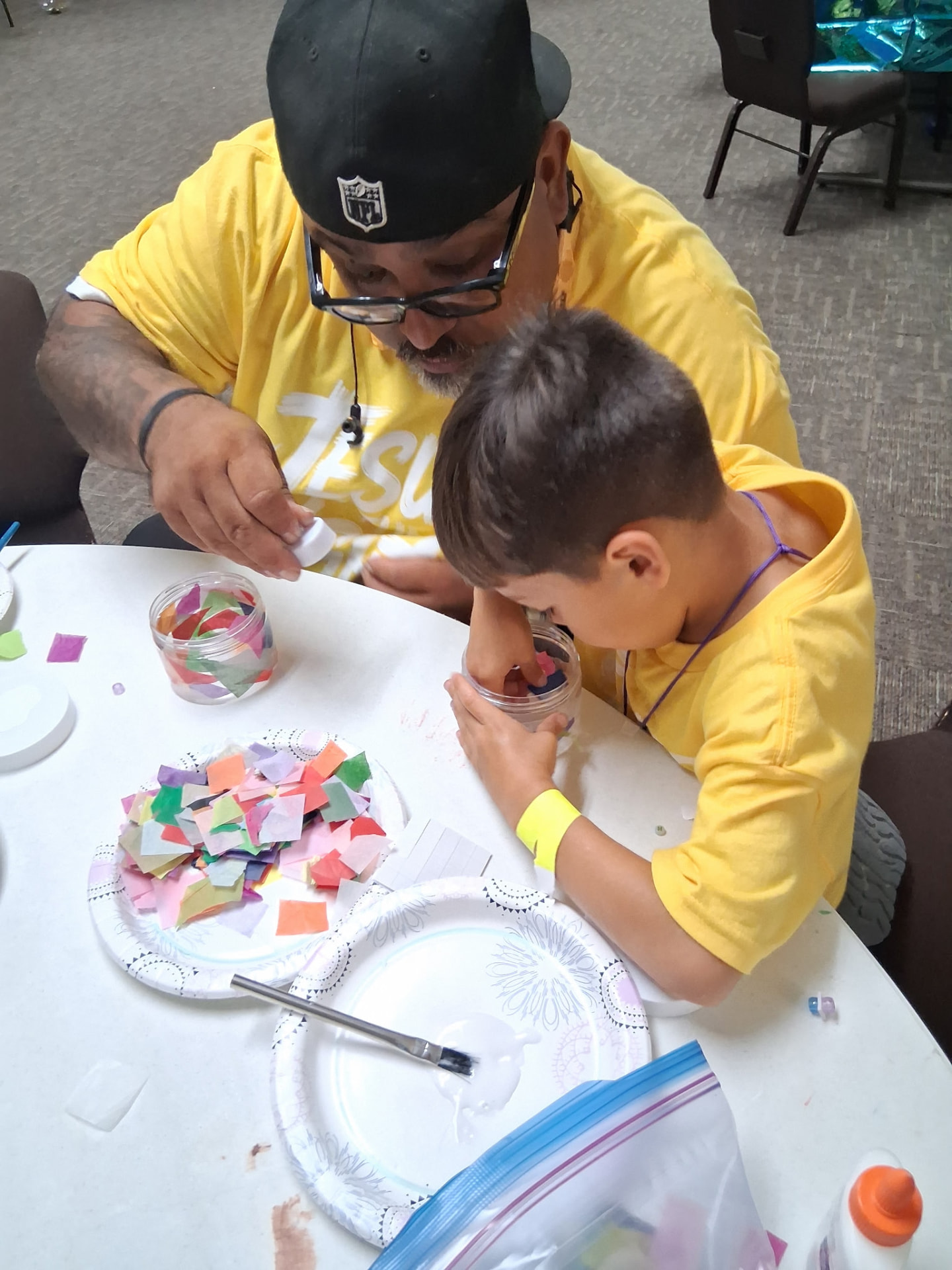 A volunteer helping a boy with a tissue-paper craft project