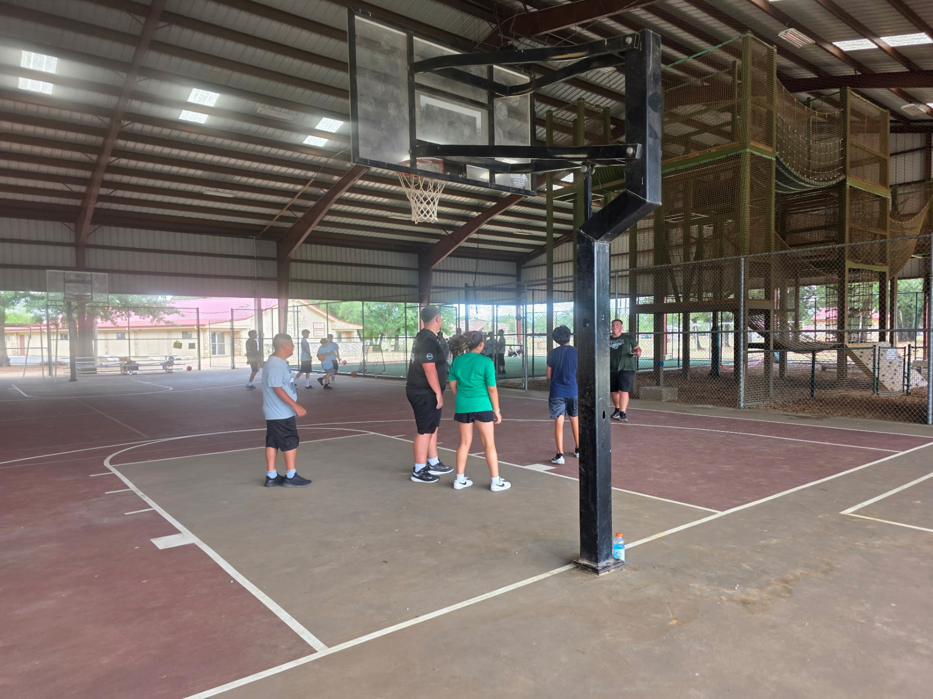 Students shooting hoops on the covered basketball court at camp