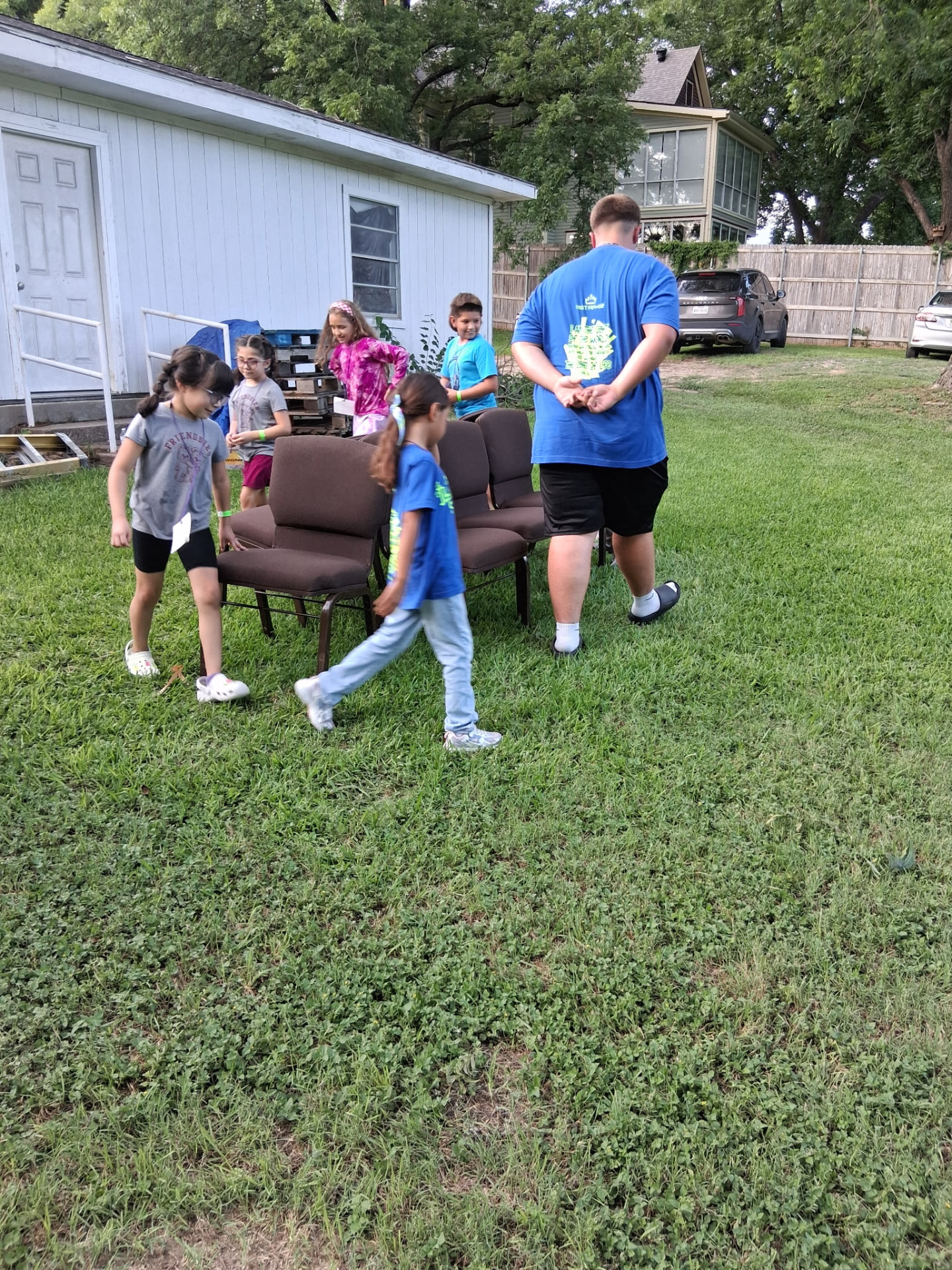 Children setting up chairs on the lawn with a volunteer leader