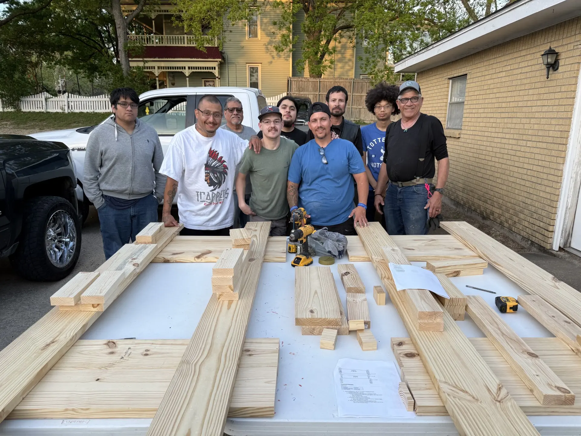 Job Corps men gathered around lumber laid out for a build project in the parking lot