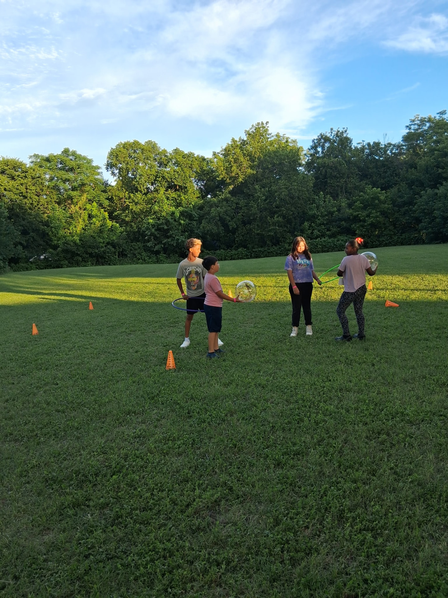 Children playing outdoor games with hula hoops in the field at sunset