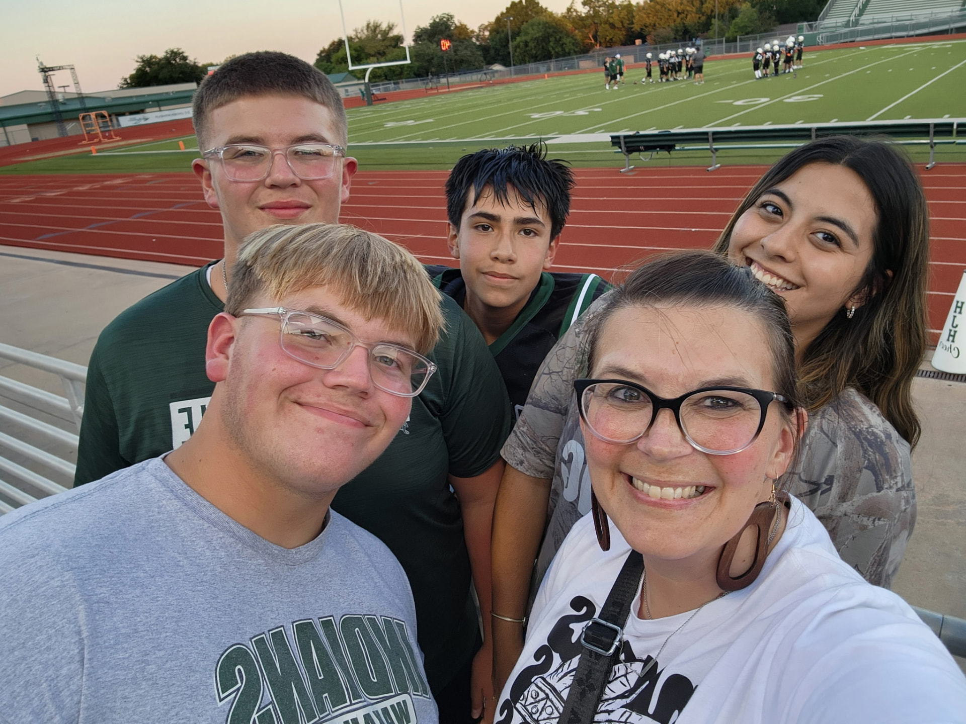 Students and a leader cheering on classmates at a Friday night football game