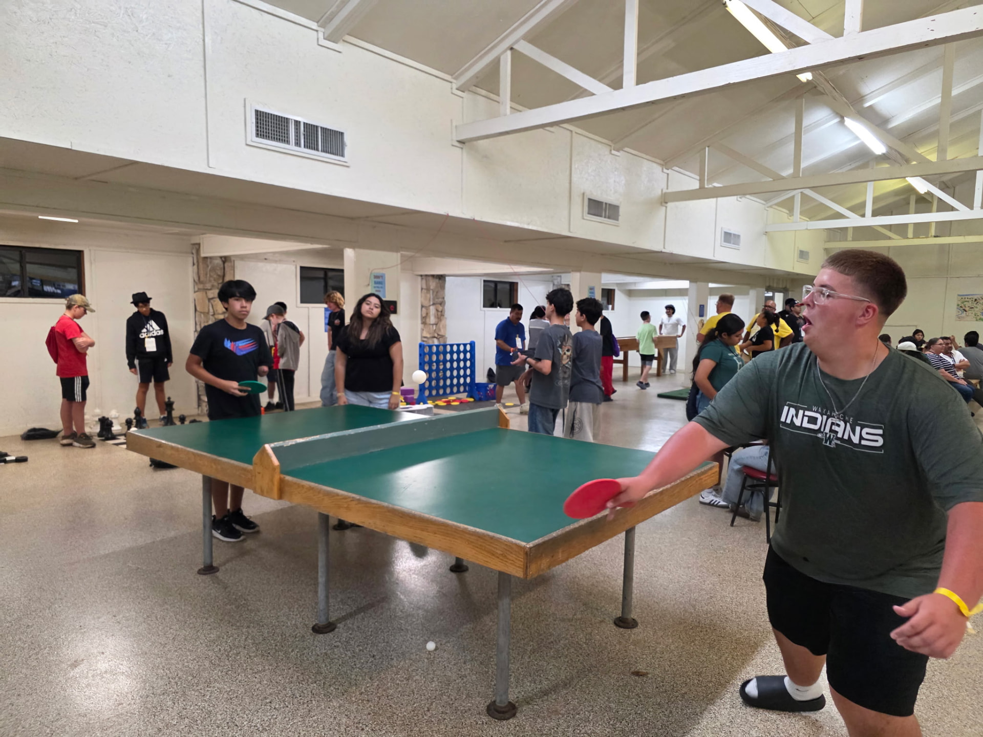 A student mid-swing during a ping pong match at camp