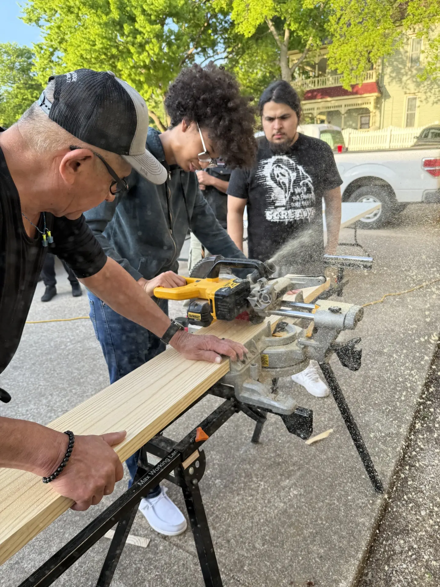 A mentor showing students how to cut lumber with a miter saw